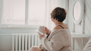 woman looking out window while enjoying morning coffee