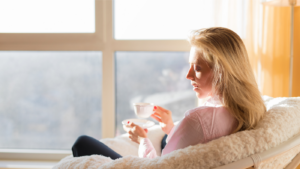 Woman drinking coffee in the morning looking out the window.