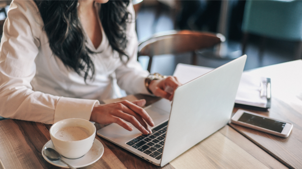woman typing on laptop with coffee nearby