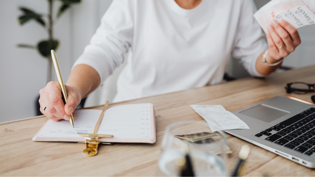 a woman's hand writing notes in planner