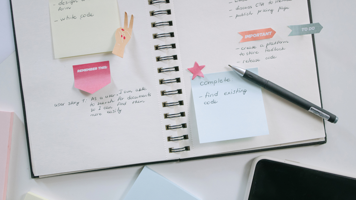 Open notebook with pastel sticky notes and a pen showing a simple system for slow business growth